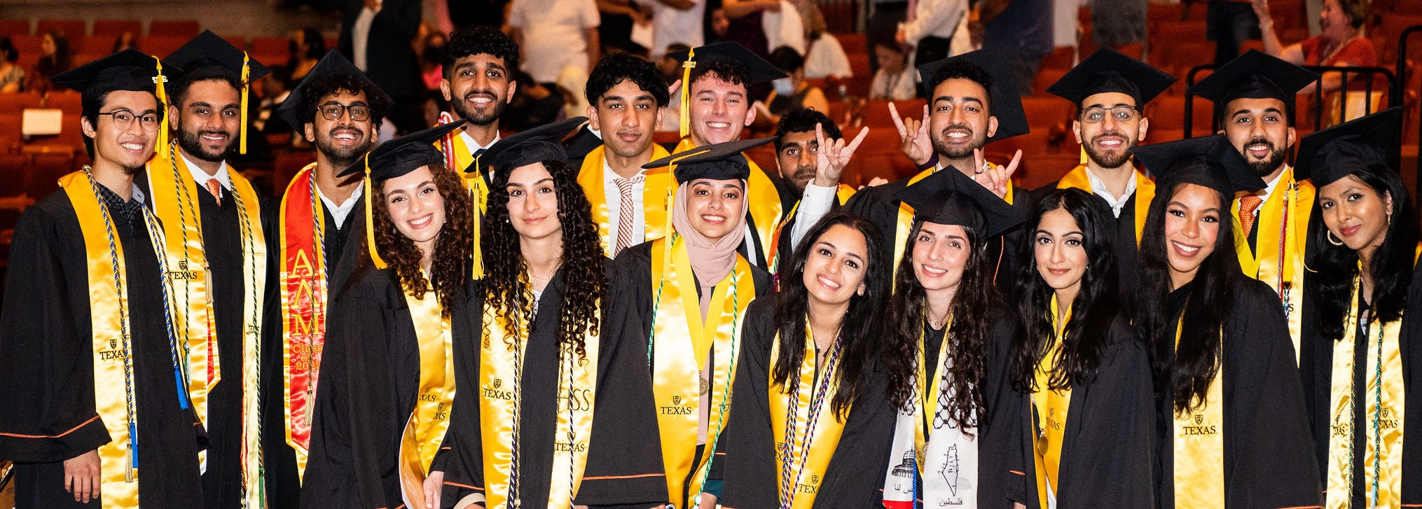 Students in caps and gowns smiling at camera
