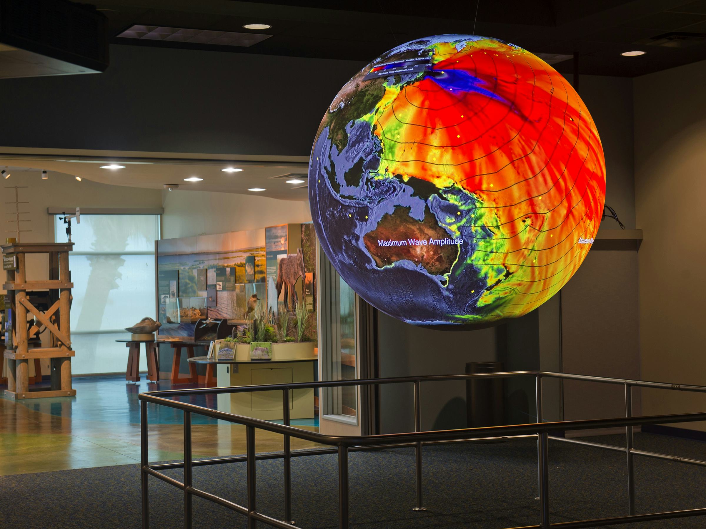 A photo of the displays at the Bay Education Center. Light projections on a sphere create the illusion of a floating earth with scientific data overlays.