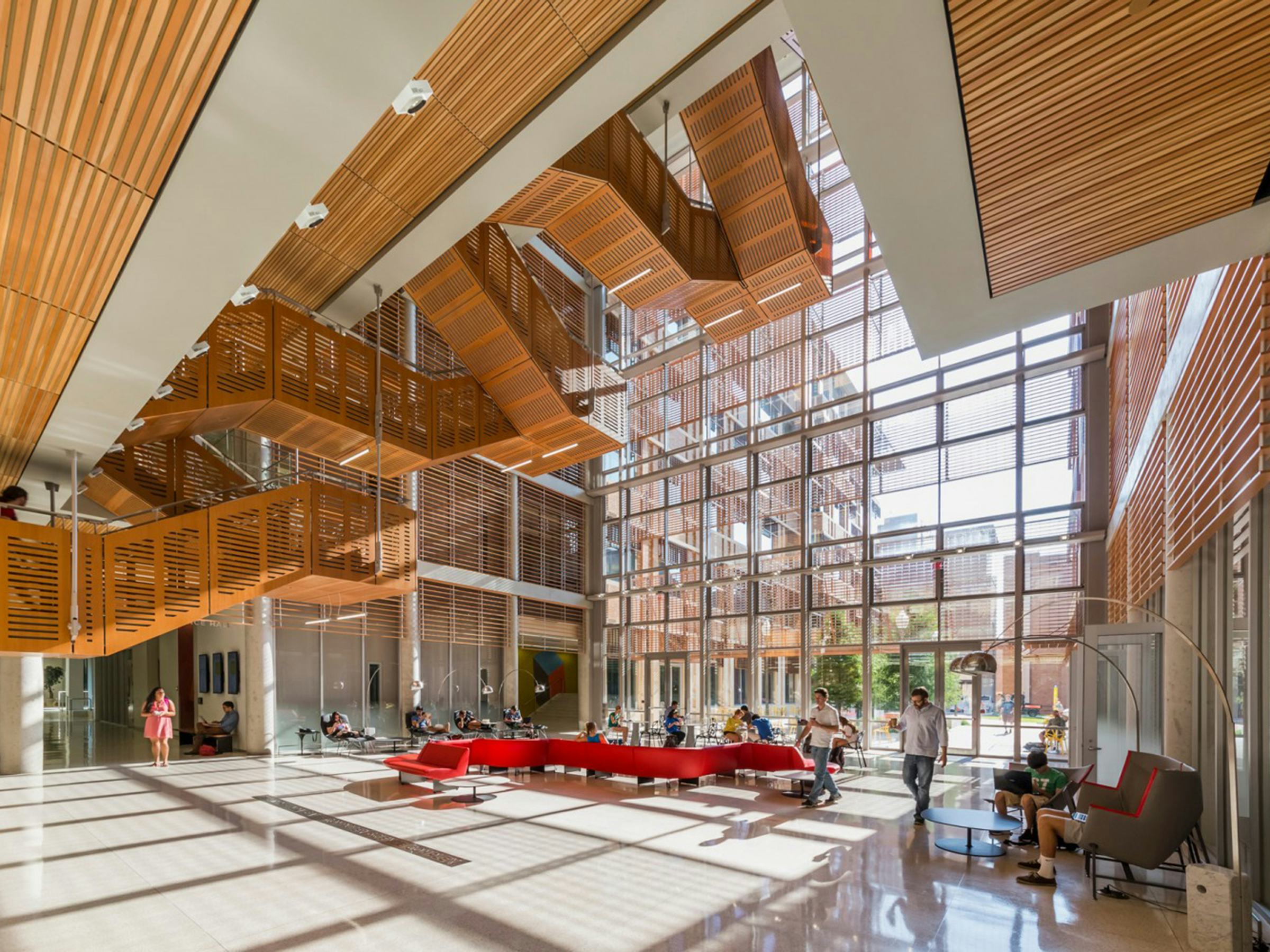 Photo of the atrium in the Gates - Dell Complex. Very high ceilings and large windows with abundant natural light and warm, wood-paneled interior accents.