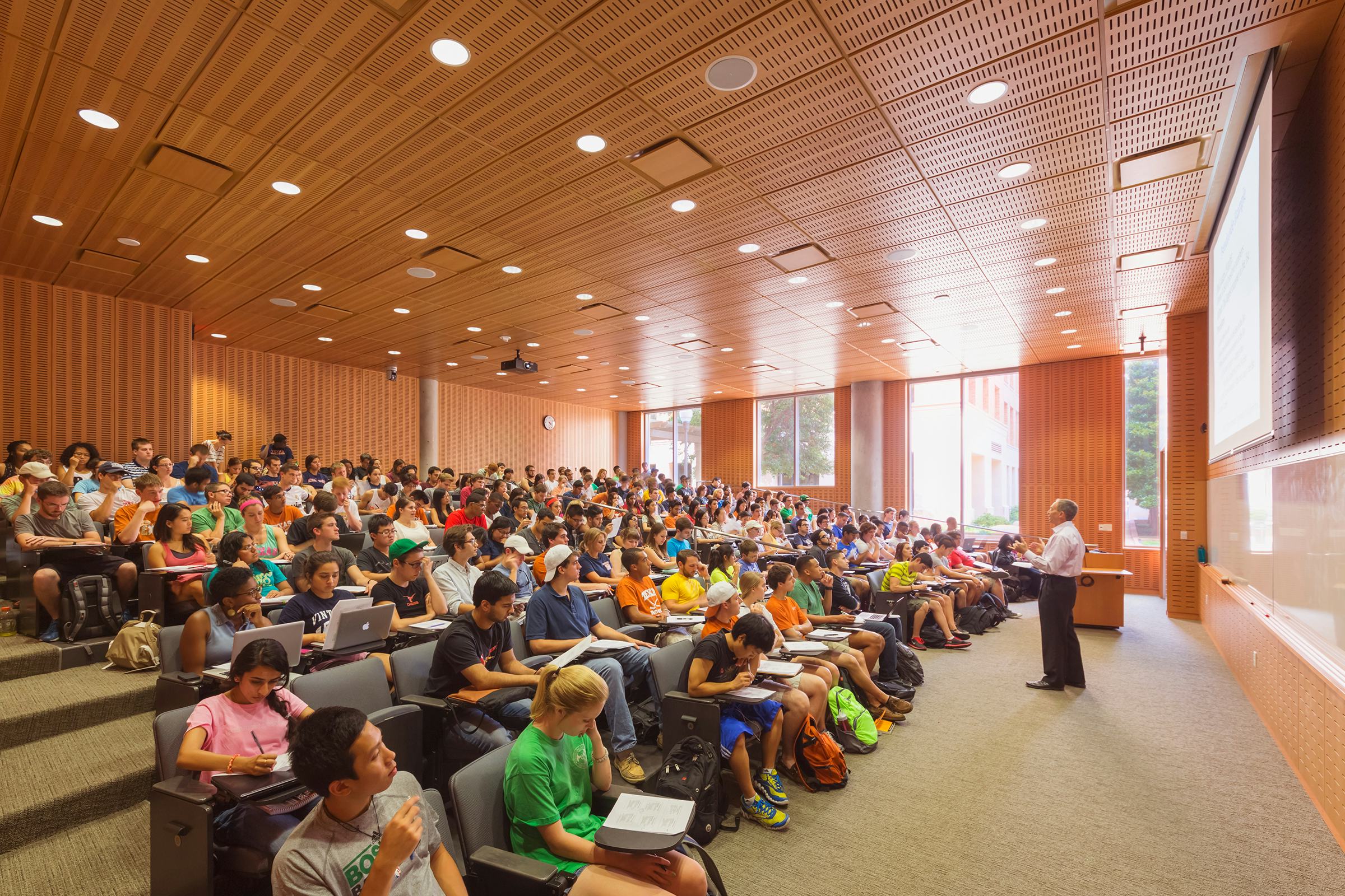 Photo of a professor standing at the front of an auditorium teaching a large class in computer science.
