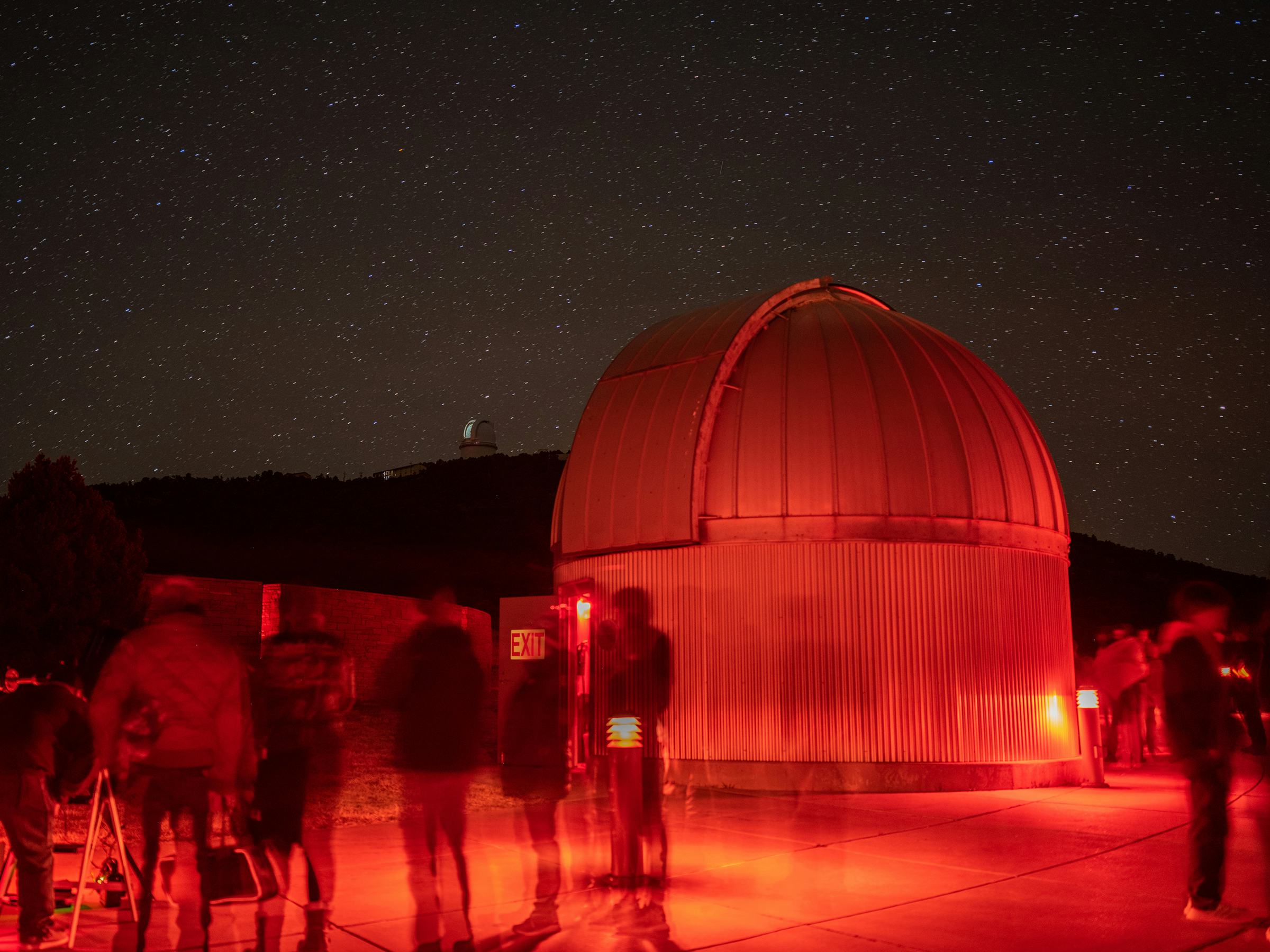 Photo of star party at the McDonald Observatory. Visitors stargazing near a large telescope at night.