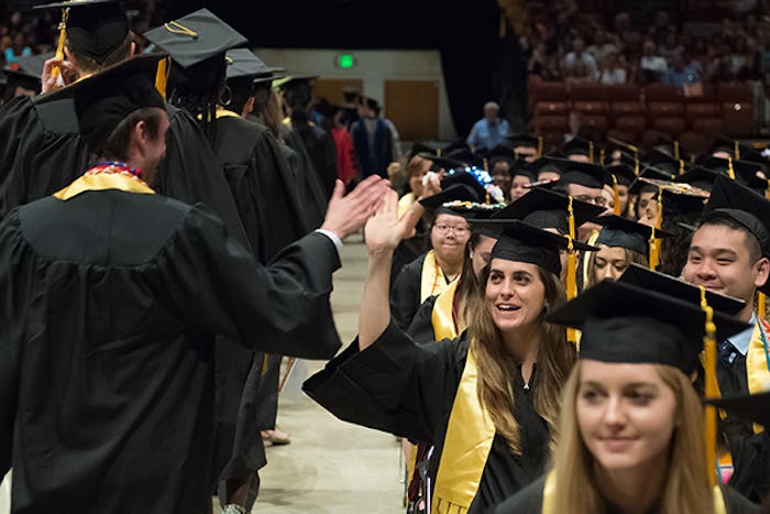 Students in graduation robes high five each other
