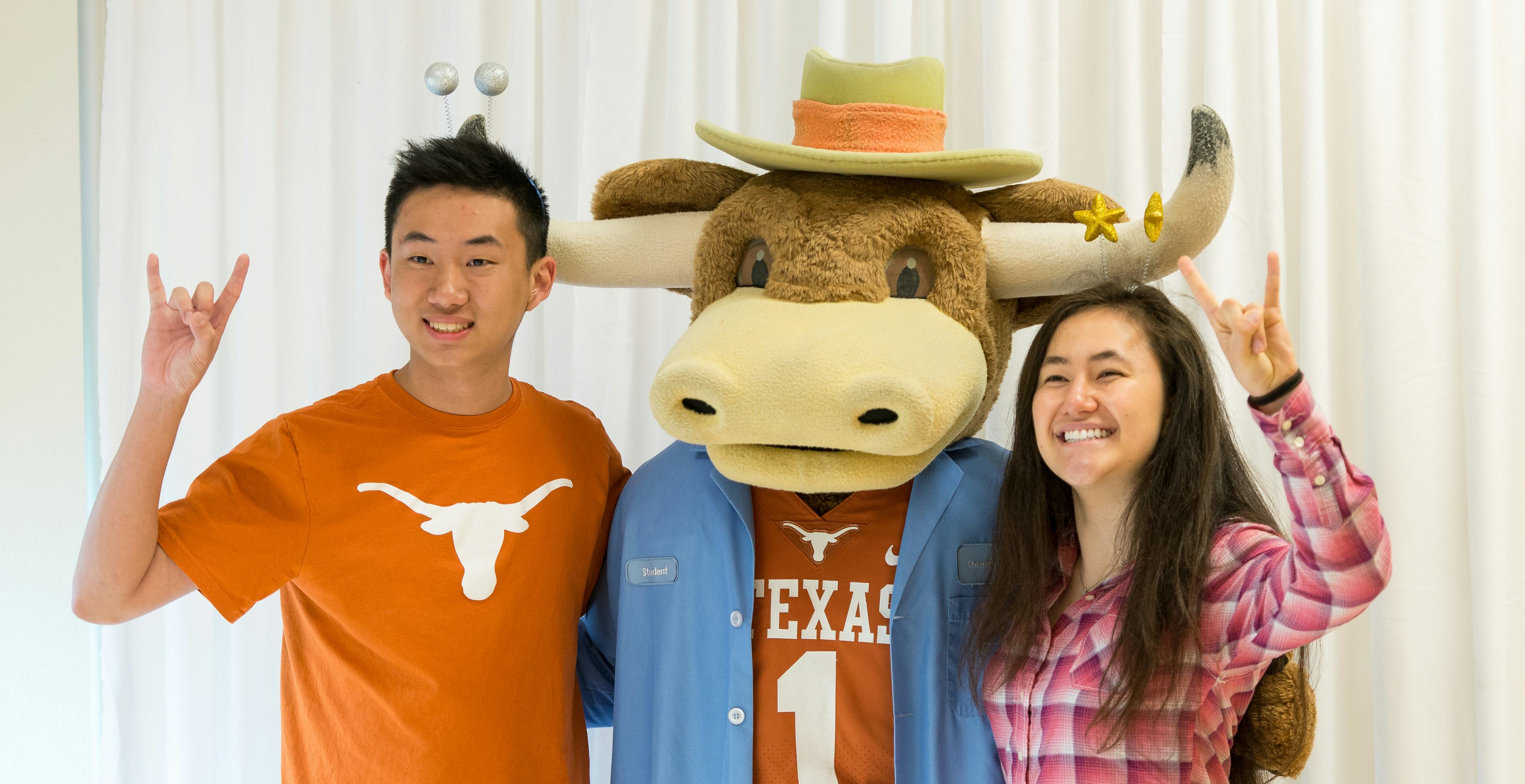 Two students with Bevo with hook em hands