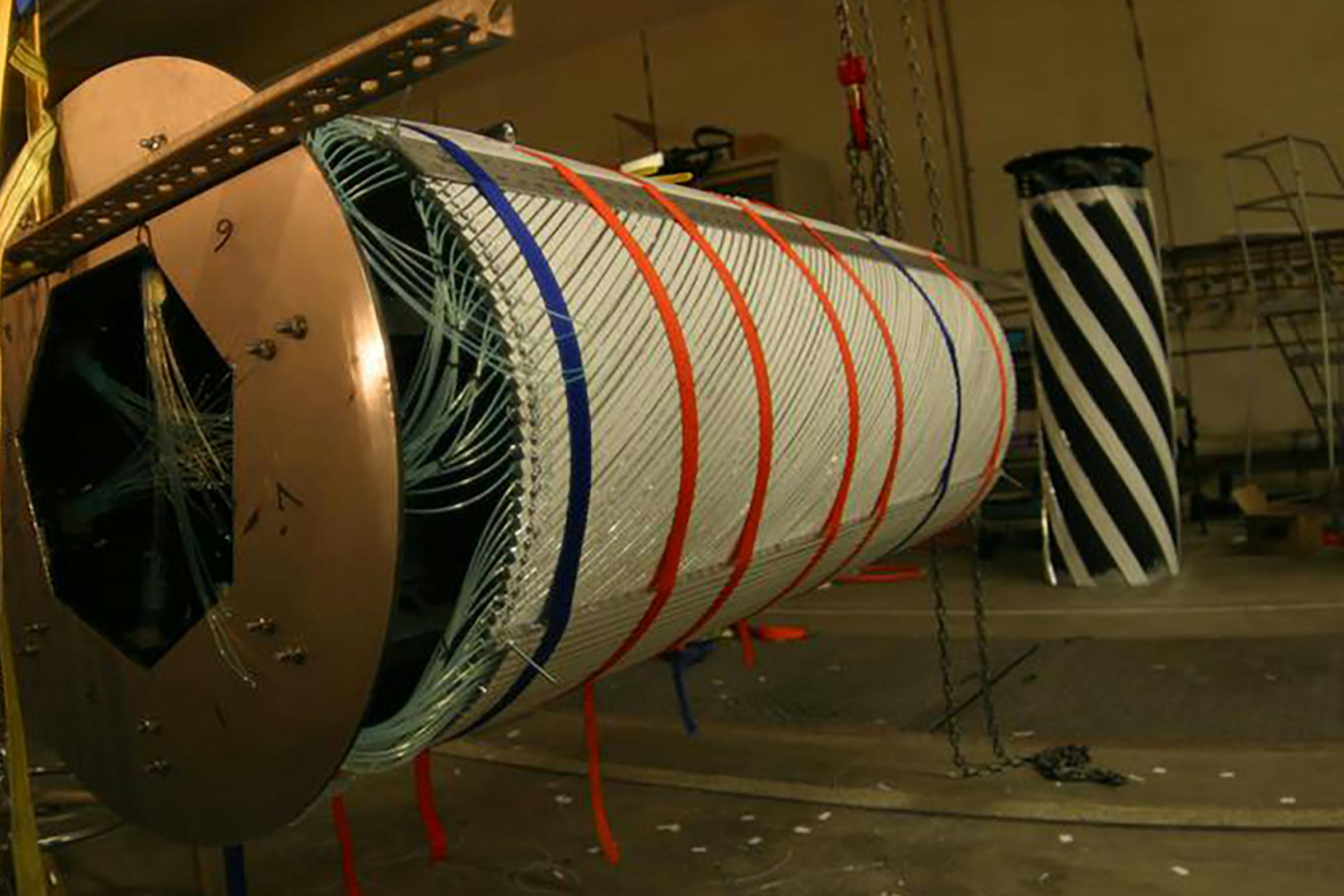 A large cylinder-shaped piece of scientific equipment hangs from chains