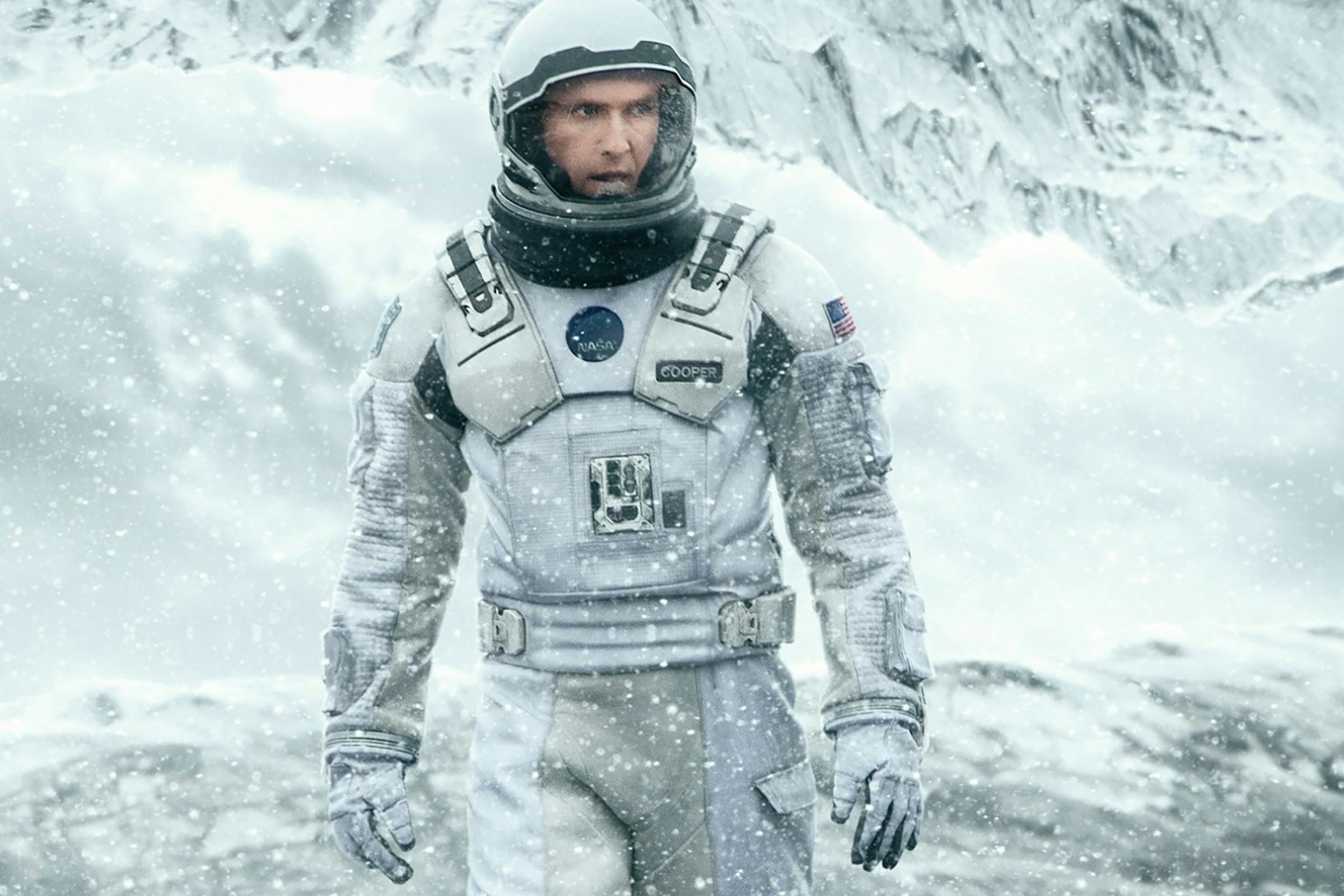 An astronaut walks across a frozen, alien landscape