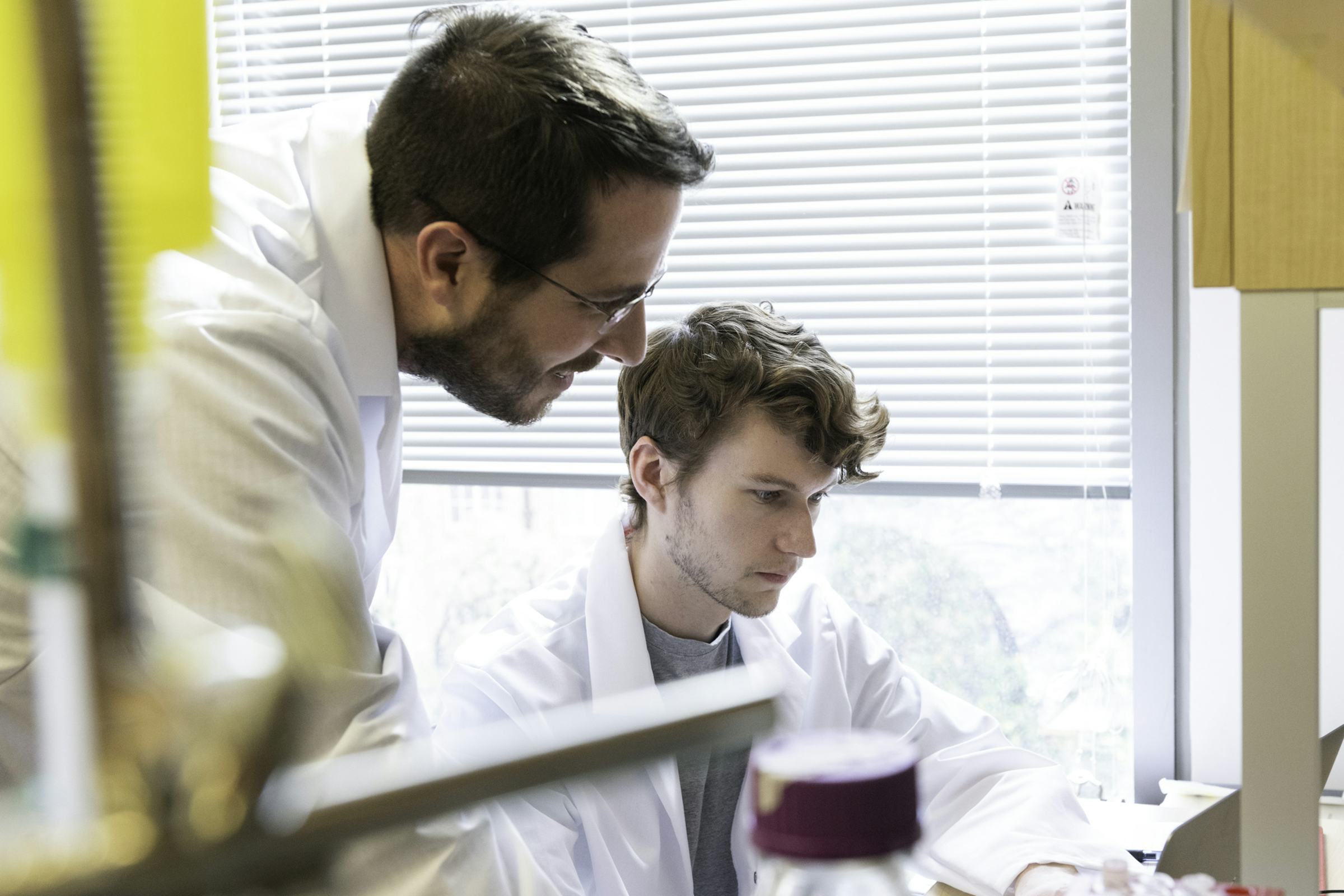 Jason McLellan peers at lab work underway by grad student Daniel Wrapp