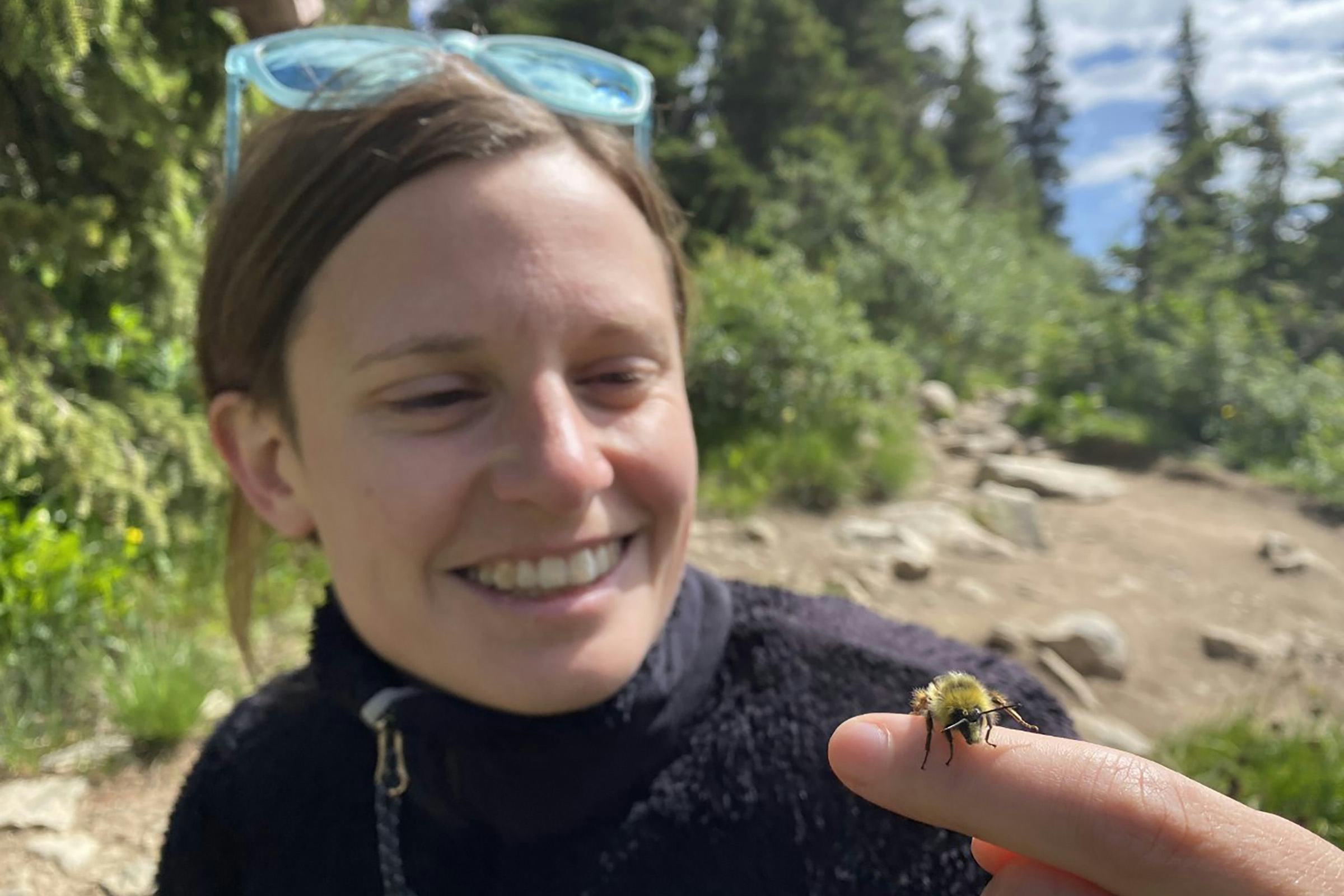 A woman looks at a bee on her finger