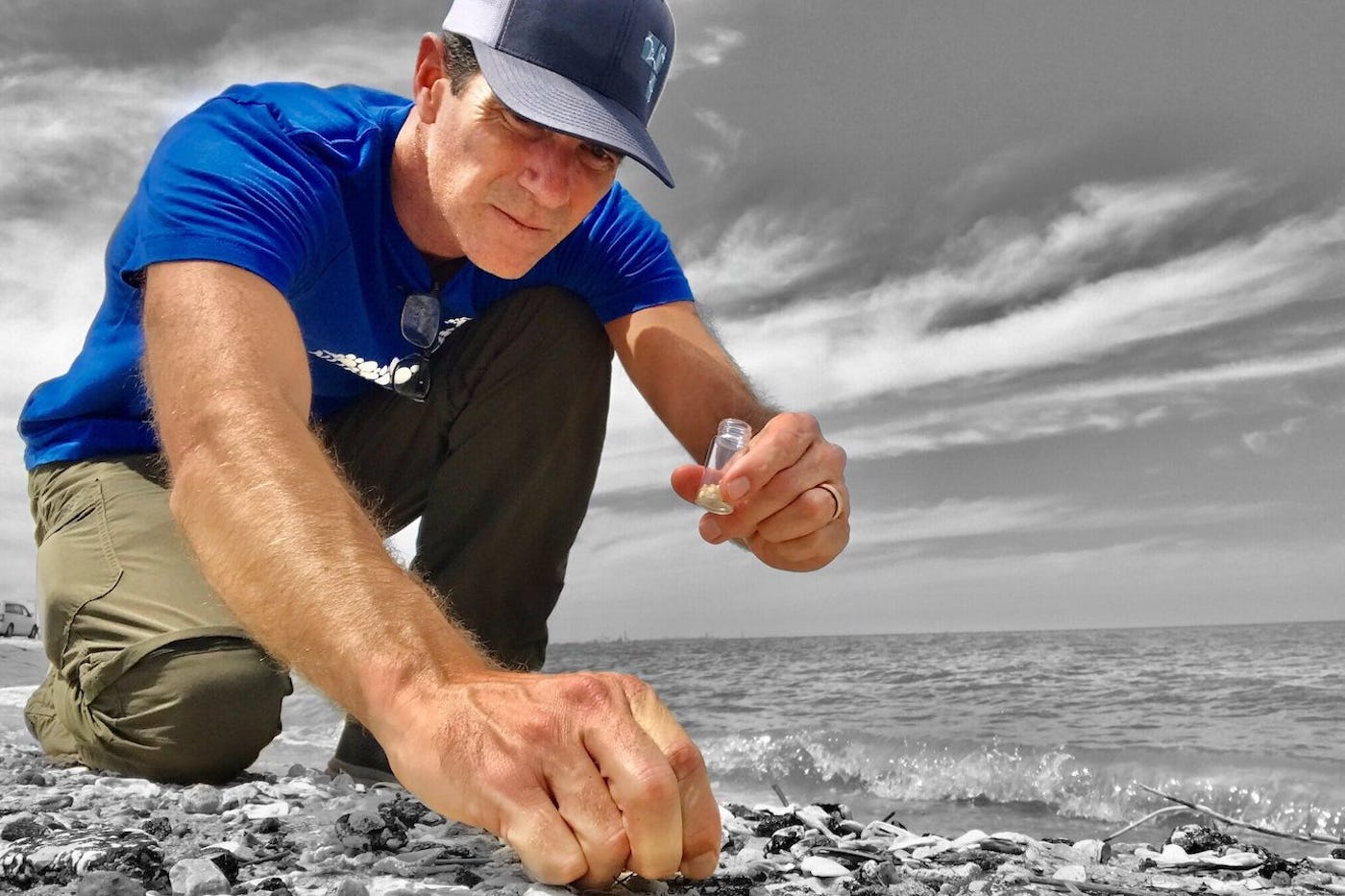 Jace Tunnell of the Nurdle Patrol on the beach crouches and picks up plastic pellets to add to a tube