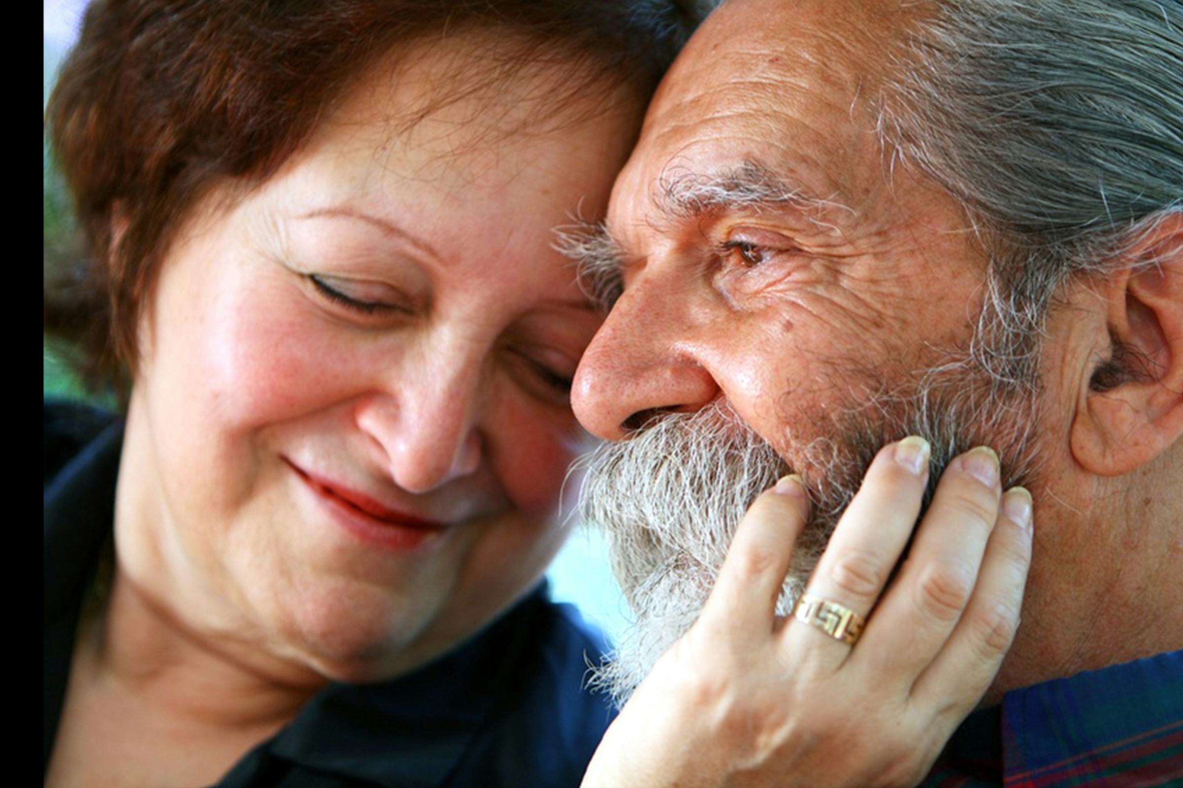 Older couple, the woman's hand rests on the cheek of the man, both look content